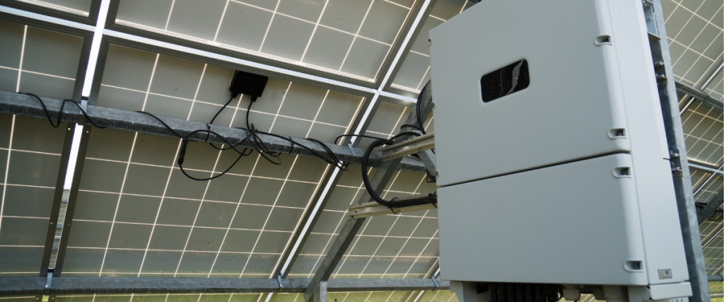 Photo of a string inverter behind a ground mounted solar array